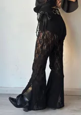 Pantalón acampanado de encaje negro con aberturas laterales y cintura alta con cinturón de cuero con hebilla metálica.