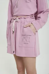 Short ancho de algodón color rosa, con cintura elástica y cordón de ajuste. Presenta un bolsillo lateral con estampado de dos perfiles y la frase "Le monde est à nous".