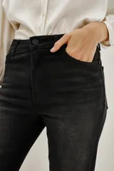 Jean negro de tiro medio con ligero efecto acampanado, lavado stone y bigotes. Presenta bordado de alas en los bolsillos traseros.