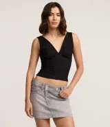 Minifalda de jeans azul oscuro, con cintura alta y cierre cruzado con botones. Presenta trabillas y bolsillos delanteros y traseros.