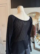 Blusa de encaje color rosa pálido con volados asimétricos y mangas largas acampanadas.