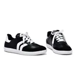 Championes deportivos de cuero sintético negro con detalles en blanco, suela blanca y cordones blancos.