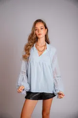 Camisa blanca de plumetí con cuello mao, mangas largas abullonadas con puños elásticos y cordón con borlas en el escote.