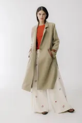 Tapado largo color beige con diseño de espiga, apliques de cuero marrón en bolsillos y mangas, tajos laterales y cierre con botón.