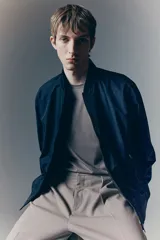 Campera bomber negra liviana con cuello elevado acanalado y cierre delantero. Tiene bolsillos laterales y un bolsillo interior, todos con cierre. Los puños y el bajo son acanalados.