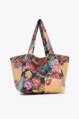 Maxi bolso de mano tipo tote bag con estampado floral multicolor sobre fondo amarillo.