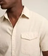 Camisa de hombre de manga corta confeccionada en una mezcla de lino y algodón, marca Marfinno. Presenta un calce confort, cuello clásico, cierre frontal con botones y un bolsillo de parche con solapa en el pecho. Las mangas cuentan con un detalle de dobladillo.
