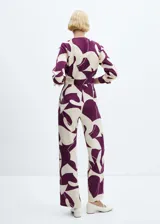 Mono largo estampado en tonos crema y morado, con diseño cruzado, cuello pico con solapa, manga larga abotonada, cinturón desmontable y forro interior.