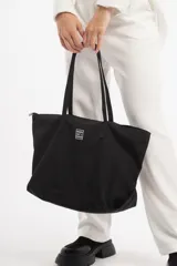 Bolso de tela negro con asas largas y diseño simple, ideal para uso diario.