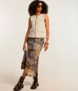 Chaleco color beige de corte sastrero con cierre frontal de cremallera, cuello redondo y bolsillos con solapa.