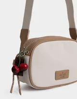 Bandolera de cuerina azul marino y beige con correa regulable azul y charm lateral decorativo. Tiene cierre superior y tag frontal con logo "The Brunch Club".