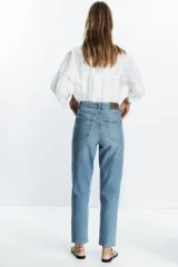 Pantalón de jean negro de corte recto, tiro alto y largo tobillero.
