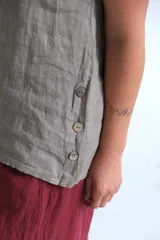 Musculosa color visón confeccionada en lino italiano, con escote redondo y botones de madera en los laterales.