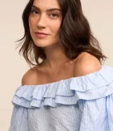 Blusa con escote hombro a hombro, confeccionada en tricolina con estampa rayada, volados en el escote y mangas cortas amplias.