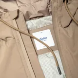 Campera color beige con capucha, cierre frontal con cremallera, bolsillos laterales y puños elásticos.