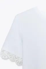 Camiseta blanca de algodón con cuello redondo y mangas cortas con detalle de encaje negro.