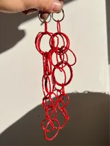 Aros colgantes hechos a mano con canutillos rojos y aritos de acero plateado.