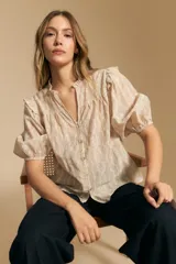 Camisa de manga corta abullonada con terminación elastizada, cuello con leve frunce y calce recto. Presenta una estampa floral integral sobre fondo claro.