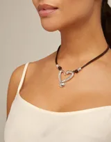 Collar Uno de 50 con doble cordón de cuero marrón y dije central de corazón plateado con forma de clavo.