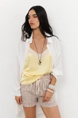 Musculosa de tirantes delgados con diseño bicolor: la parte superior es de color crema y la parte inferior es de color rosado pálido, ambas con acabado satinado.