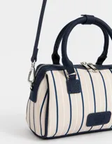 Cartera bowling con estampado de rayas verticales color beige y azul marino. Tiene doble asa corta de mano y correa regulable y desmontable. Incluye cierre superior y tag frontal de cuerina con el logo 'The Brunch Club'.