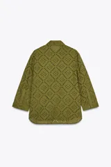 Camisa amarilla de cuello solapa y manga larga acabada en puño. Detalle de bordados perforados a tono. Cierre frontal con botones ocultos por solapa.