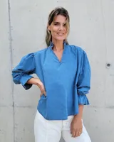 Blusa de denim azul con manga larga abullonada y cuello alto.