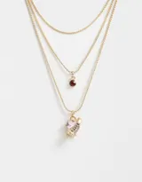 Collar dorado multicadena con dije de corazón rosa y dije de cristal rojo.
