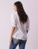 Blusa blanca calada con escote en V, mangas cortas con hombros fruncidos y puños elastizados.