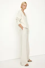 Pantalón recto color crema de tejido vaporoso en mezcla de lino. Modelo holgado con elástico y cordón de ajuste en la cintura, bolsillos laterales y traseros insertados.