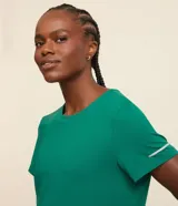 Remera deportiva blanca texturizada, con cuello redondo, manga corta, detalle reflectante y pliegue en la espalda.