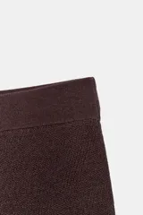 Falda midi color marrón oscuro, de punto, tiro alto, cintura elástica y bajo asimétrico con volados.