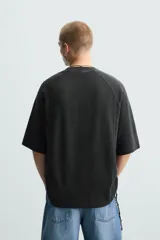 Camiseta negra de corte holgado, cuello redondo y mangas cortas. Tiene un efecto de lavado que le da una apariencia única.