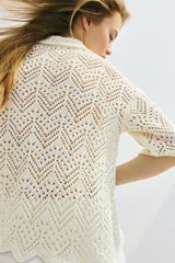 Camisa color crema de tejido crochet con cuello clásico, cierre frontal con botones y mangas cortas.