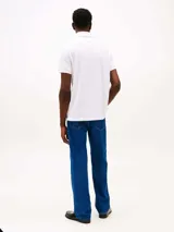 Chomba blanca de manga corta con cuello polo y tapeta de dos botones. Diseño con corte regular y logo de Tommy Hilfiger bordado en el pecho.