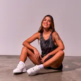 Musculosa deportiva negra con estampado de líneas diagonales blancas y logo de New York en el pecho.