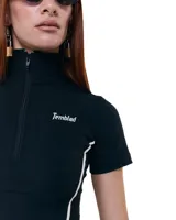 Top negro cropped de gabardina elastizada, con cuello alto, cierre frontal y mangas cortas. Diseño entallado con recortes y costuras a contratono blancas. Logo Temblad en el pecho.