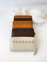 Billetera de cuero color camel con cierre metálico, diseño con textura símil piel de cocodrilo y detalle de costuras cruzadas en el frente. Incluye monedero interno y espacio para billetes extendidos.