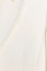 Blazer color blanco confeccionado en algodón, con cuello solapa de muescas y manga larga. Tiene bolsillos con solapa en delantero, forro interior a tono y cierre frontal con botones metálicos en relieve.