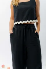 Top de lino color crudo, con escote cuadrado y detalle de guarda ondulada negra en el ruedo.