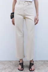 Pantalón de jean de tiro alto color negro con pierna ancha, bolsillos delanteros y traseros, y cierre frontal con cremallera y botón metálico.