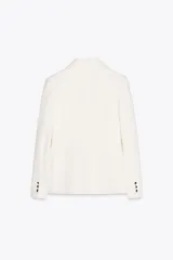 Blazer color blanco confeccionado en algodón, con cuello solapa de muescas y manga larga. Tiene bolsillos con solapa en delantero, forro interior a tono y cierre frontal con botones metálicos en relieve.
