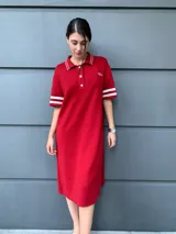 Vestido rojo de corte recto, con cuello polo, cierre de botones parcial, mangas cortas con doble franja blanca y logo bordado en el pecho.