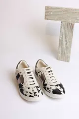 Zapatillas deportivas bajas con estampado animal print de vaca en blanco y marrón.