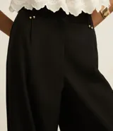 Pantalón negro de vestir, corte wide leg, cintura alta con doble pretina y detalle de remaches.