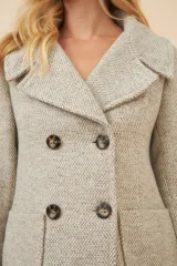 Chaquetón color crema con doble solapa, abrochadura doble, bolsillos delanteros y forro al tono.