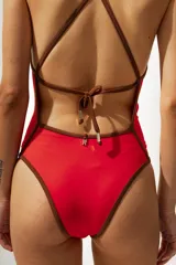 Malla enteriza roja con breteles finos marrones y ribete marrón en escote y cavado de pierna.