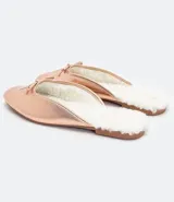 Zapatilla mule color rosa metalizado, con punta redonda, lazo decorativo en la parte superior, interior de piel sintética y suela plana.
