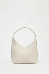 Bolso tipo saca de cuero color gris claro con textura granulada. Tiene asa de hombro y cierre con imán. Incluye cartera interior extraíble con bolsillo.