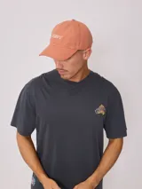 Gorra de lona color salmón con logo de la marca bordado en blanco.
